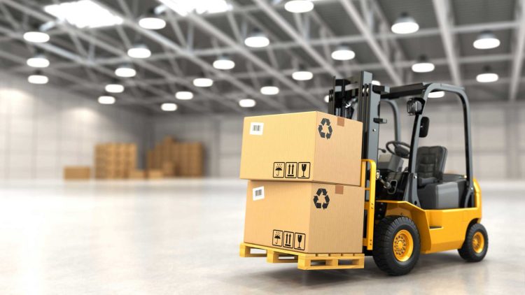 Yellow counterbalance forklift transporting two large boxes in a warehouse