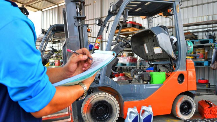 Worker performing forklift preventative maintenance on warehouse equipment