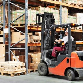 Operator using a sit-down forklift to store pallets in a warehouse
