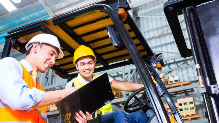 Two warehouse workers going down their spring forklift maintenance guide for their vehicle.