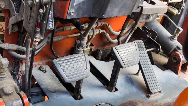 Performing a forklift brake inspection on orange forklift equipment