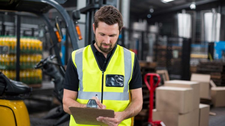 Forklift operator using a checklist to inspect a warehouse forklift