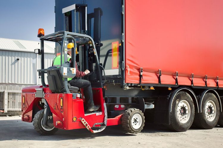 Operator dismounting a truck-mounted forklift from a semi-trailer