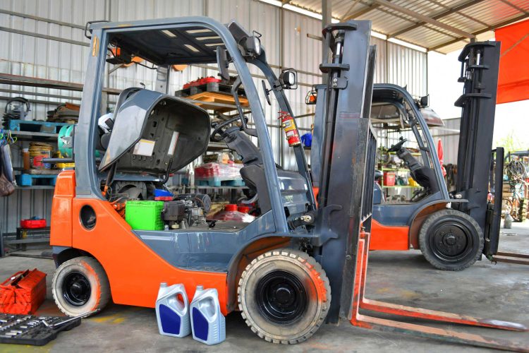 Orange warehouse lift truck in the shop undergoing forklift maintenance