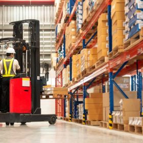 Operator using a turret lift to move pallets in a packed warehouse