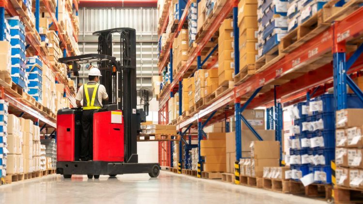 Operator using a turret lift to move pallets in a packed warehouse