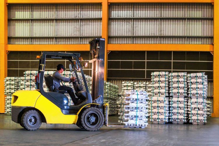 Male operator using a warehouse forklift to move pallets