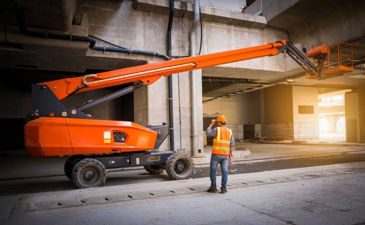 Operator inspecting an electric man lift indoors