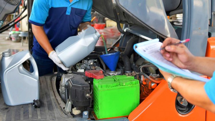 Professional servicer adding forklift oil to a forklift