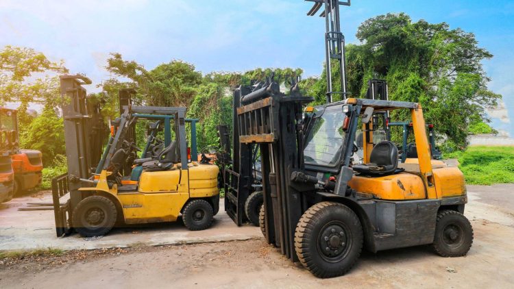Two pre-owned forklifts for sale with pneumatic tires parked outside