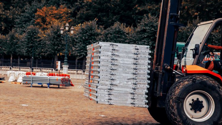A powered industrial truck going through an outdoor warehouse in fall.