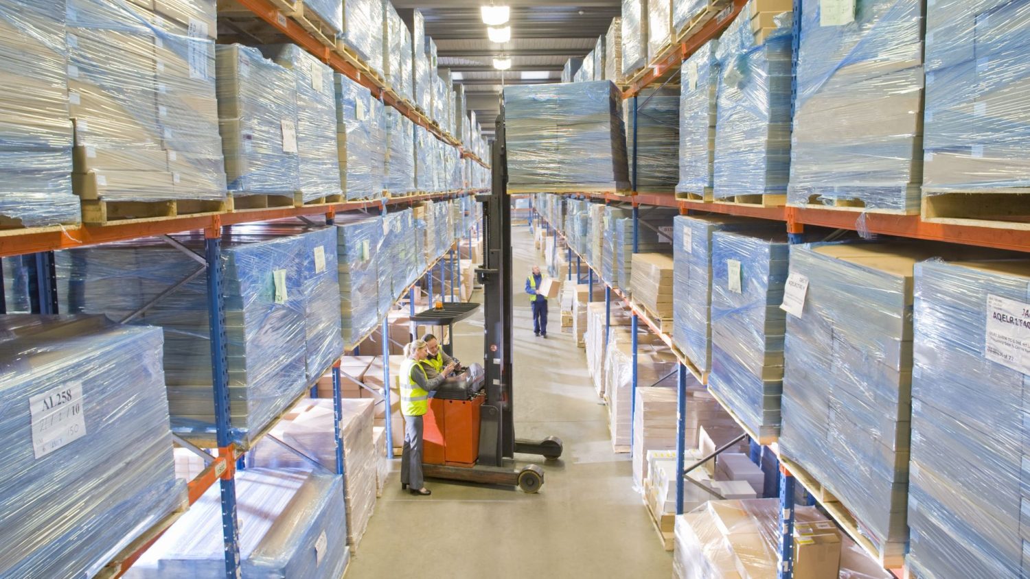 Narrow aisle reach truck between narrow aisles in a warehouse.