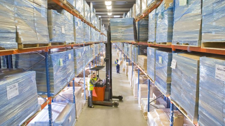 Narrow aisle reach truck between narrow aisles in a warehouse.
