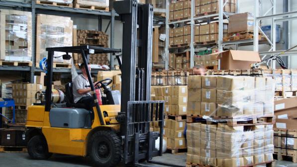 Forklift operator using a used forklift in a warehouse