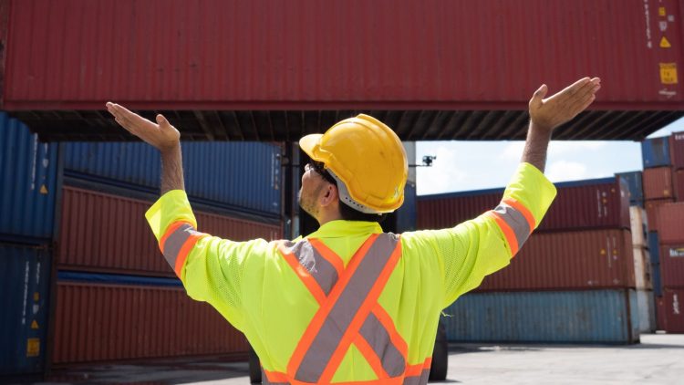 Worker using forklift hand signals to communicate to the forklift operator